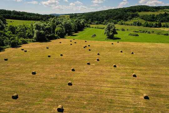 Landscape drone photograph with hay bales arranged on a pasture in summer season