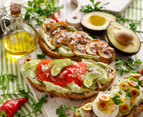 Vegetarian sourdough bread sandwiches with avocado paste and various toppings, focus on the sandwich inside with tomato slices and cucumber close up view