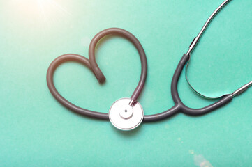 Stethoscope in Shape of Heart Isolated On Green Background.