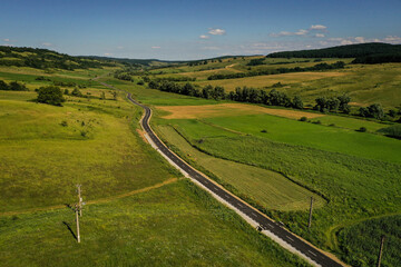 Fototapeta na wymiar Drone photograph with new asphalt road crossing a beautiful hilly landscape in summer season