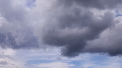 Obraz premium Heavy low gray rain clouds, covering the blue sky. One cloud in the center resembles a heart.