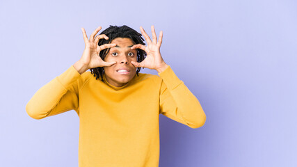 Young black man wearing rasta hairstyle keeping eyes opened to find a success opportunity.