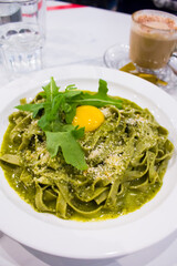Fettuccine with Creamy Pesto and egg yolk in the middle. White background. 