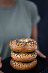 A Women's hands holding a plate full of Bagels on a Black Background