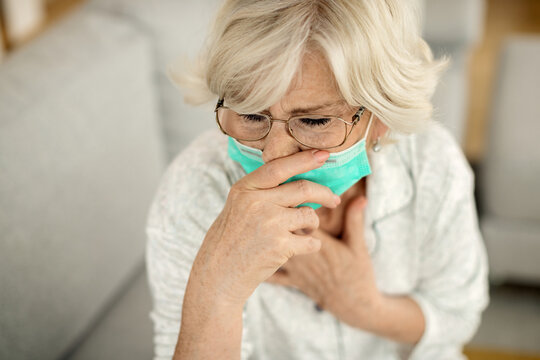 Sick Mature Woman With Face Mask Coughing At Home.