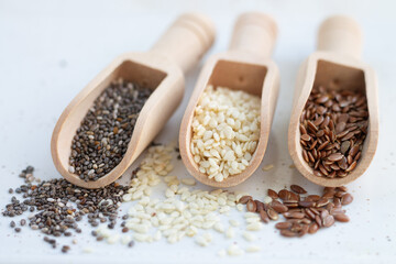 Wooden scoops with chia, flax and white sesame seeds close-up