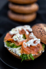 Salmon Lox Bagel with cream cheese and veggies on a dark setting