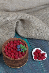 No-bake chocolate cake with cream cheese. Garnished with raspberries, blueberries and mint leaves. On the surface of pine boards painted in black and green.