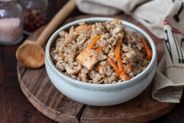 Pearl barley porridge with meat and vegetables on a wooden background