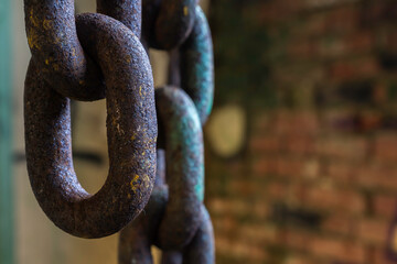 A solitary link hanging from a heavy industrial chain.