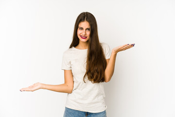 Young caucasian woman isolated on white background confused and doubtful shrugging shoulders to hold a copy space.