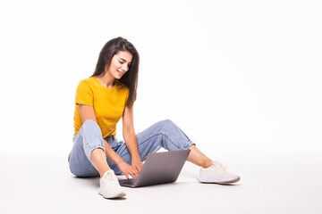 Young woman sitting on the floor and using laptop on white background