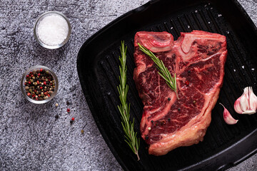 Fresh raw t-bone steak on frying grill pan.