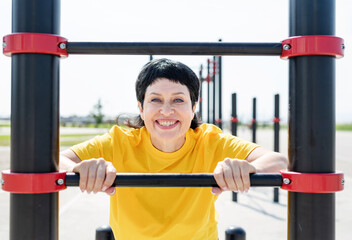 Smiling senior woman doing push-ups outdoors