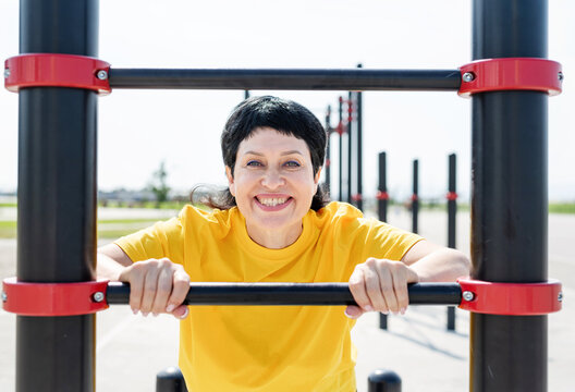 Smiling senior woman doing push-ups outdoors