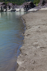 The coastline of the mountain river Katun and a sandy beach against the backdrop of rocky stones in Altai. Background for wallpaper, post or illustrations in social networks.