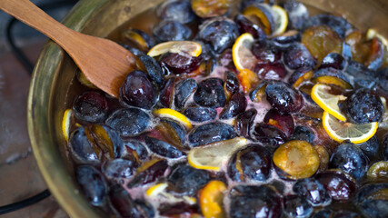 Fototapeta premium Cooking plum jam with lemon and spices in a copper basin on gas stove