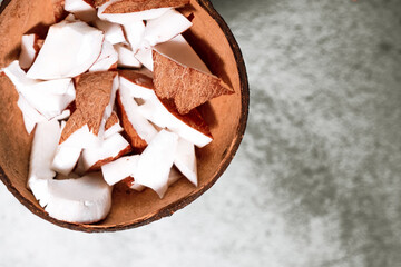 A bowl of coconut pieces on concrete background. Coconut ingredient on plate. Vegan organic snack...
