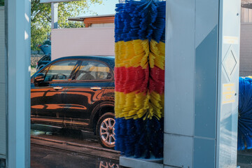 Black car is washing in an automated car wash. Car wash service close-up. 