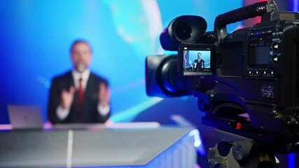Professional TV Camera Standing in Live News Studio with Anchor seen in Small Display. Unfocused TV Broadcasting Channel with Presenter, Newscaster Talking. Mock-up Television Channel Newsroom Set