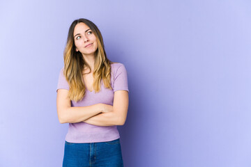 Young caucasian woman isolated on purple background dreaming of achieving goals and purposes