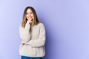 Young caucasian woman isolated on purple background smiling happy and confident, touching chin with hand.