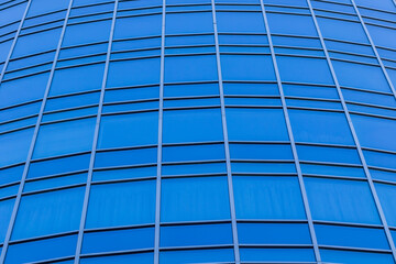 The bright blue sky is reflected in the windows of a modern glass building. Abstract fragment of a modern building. Sunny day.