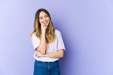 Young caucasian woman isolated on purple background relaxed thinking about something looking at a copy space.