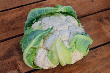 Cauliflower with leaves on a wooden background.