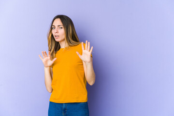 Young caucasian woman isolated on purple background being shocked due to an imminent danger