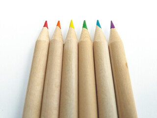Aerial perspective view of biodegradable wooden pencils, tipped with gay flag colors, isolated on white background. Vertical position of crayons background. School supplies and back to school pattern.