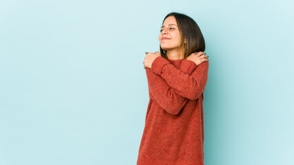 Young woman isolated on blue background hugs, smiling carefree and happy.