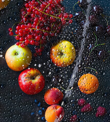 Fresh different fruits and berries, apple, apricot, currant, raspberry, chilled under dewed glass on black background