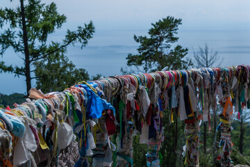 multicolored ribbons on the railing of the terrace against the backdrop of the landscape of blue lake Baikal