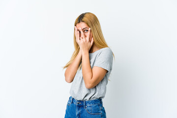 Young blonde woman isolated on white background blink through fingers frightened and nervous.