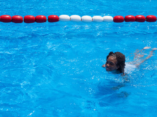 Portrait of Cute little girl African-American in swimming suit sitting in a water pool on a summer...
