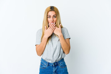 Young blonde woman isolated on white background shocked covering mouth with hands.