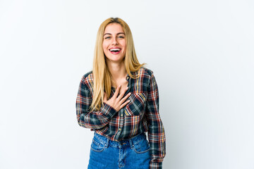 Fototapeta premium Young blonde woman isolated on white background laughs out loudly keeping hand on chest.