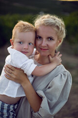 Fototapeta premium blonde woman in a dress holds her baby boy in her arms