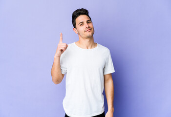 Young caucasian man isolated on purple background showing number one with finger.