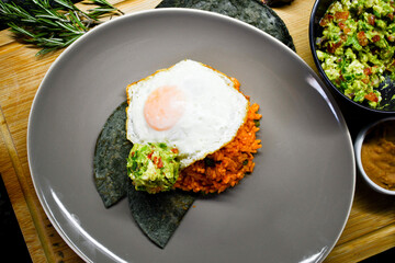 Delicioso desayuno tradicional mexicano, huevo con arroz, guacamole y tortilla de maíz azul. 