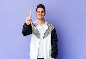 Young caucasian man isolated on purple background showing number one with finger.