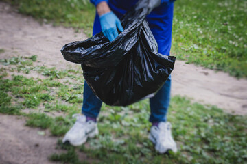 Team group of young people, girls and boys volunteering and participate in community work cleaning day, activists collecting waste, rubbish, garbage and litter in bags in the city park together