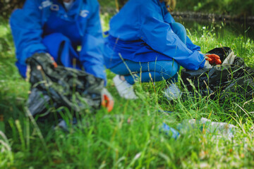 Team group of young people, girls and boys volunteering and participate in community work cleaning day, activists collecting waste, rubbish, garbage and litter in bags in the city park together