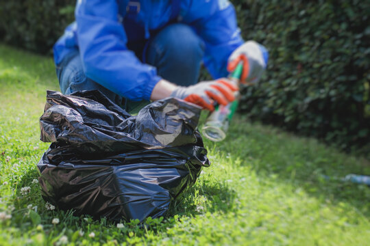 Team group of young people, girls and boys volunteering and participate in community work cleaning day, activists collecting waste, rubbish, garbage and litter in bags in the city park together