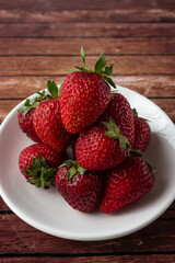 Fresh strawberries on a dark wooden table on a balow plate