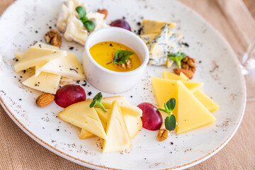 cheese platter. A plate with a variety of cheeses. Snacks. Glass of wine with cheese.