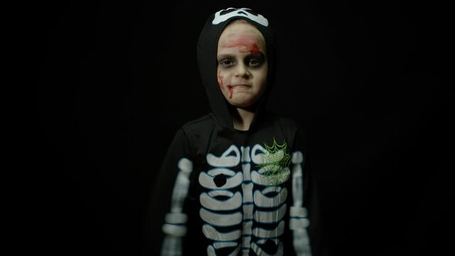 Halloween angry girl with blood makeup on face. Kid dressed as scary skeleton, dancing, making faces