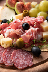 Tipico tagliere di antipasti misti con prosciutto crudo, salame, formaggi, olive e frutta fresca, Cucina Italiana