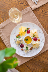 cheese platter. A plate with a variety of cheeses. Snacks. Glass of wine with cheese.